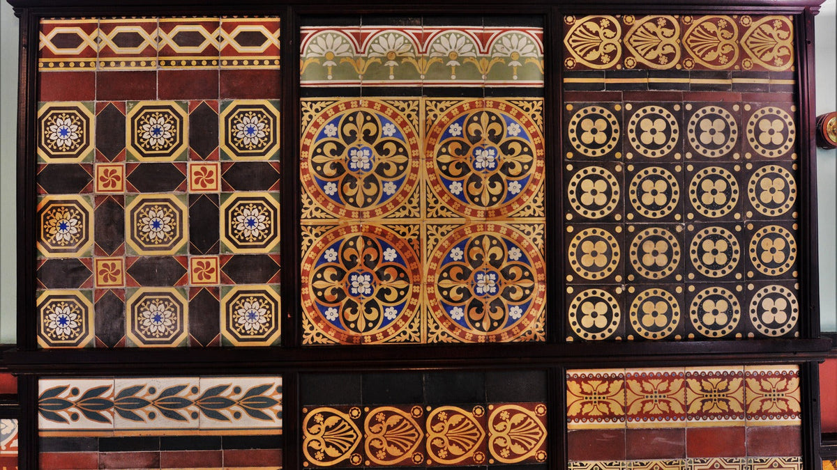 Historic tile display at Jackfield Tile Museum arranged in contrasting geometric panels of burgundy, gold, black and blue.