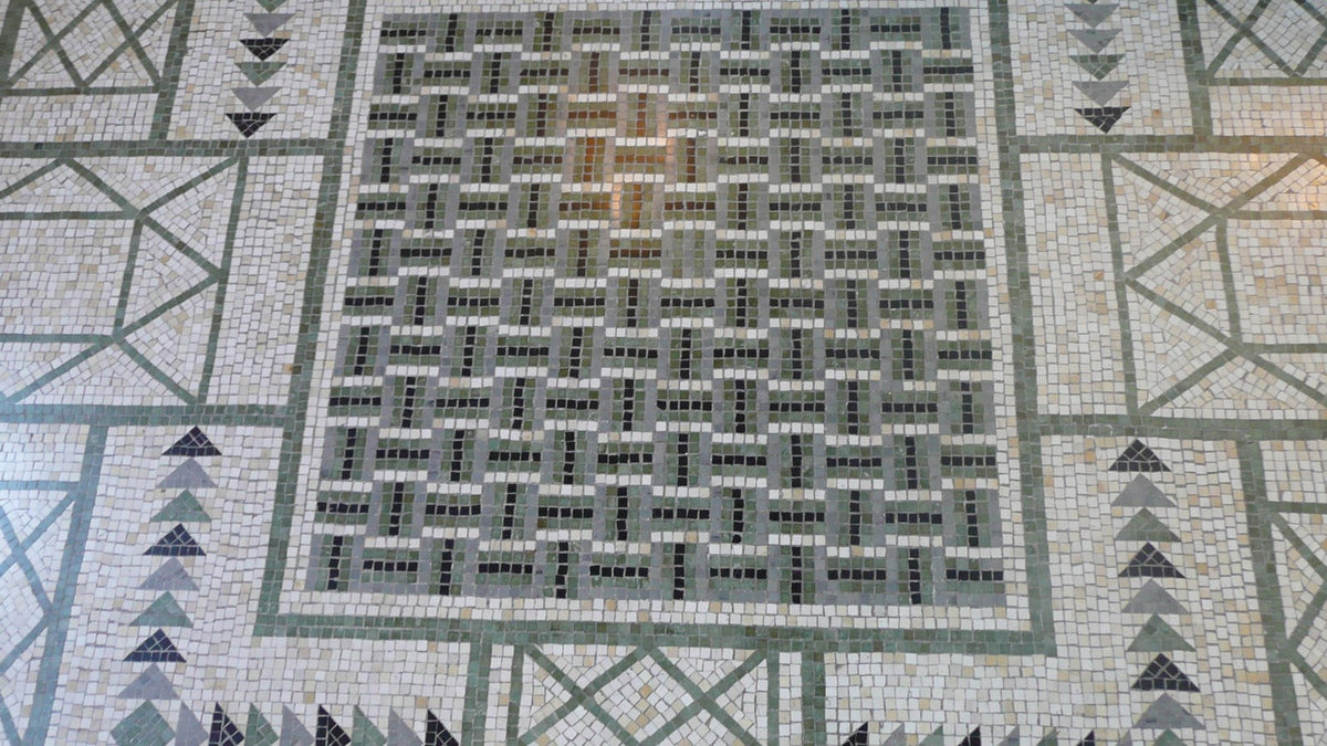 Geometric mosaic floor in pale stone and green tesserae before Theodore Reinach's bath at Villa Kerylos.