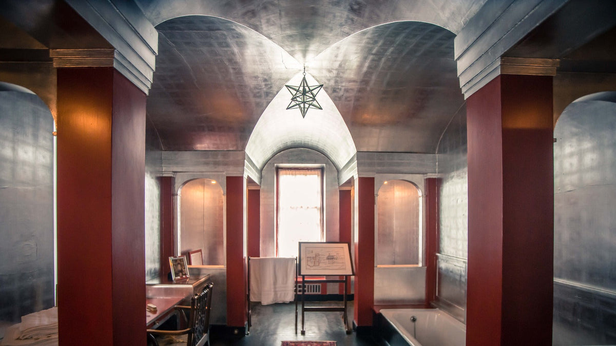 Symmetrical Art Deco bathroom at Upton House with silver barrel vaults, red columns and a star-shaped pendant.