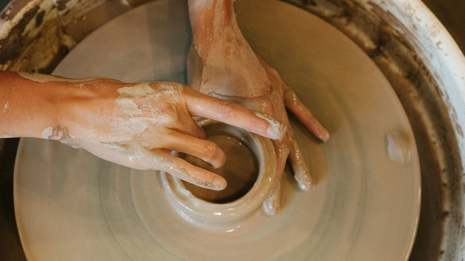 Potter's hands shaping wet clay on a wheel