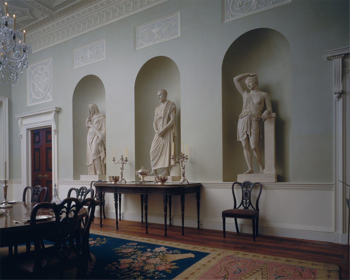 Neoclassical dining room with carved wood doors, a decorative plaster ceiling, and a marble chimneypiece.