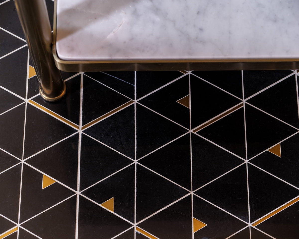 Eclipse black geometric stone floor with white lines and small brass accents beside a vanity.