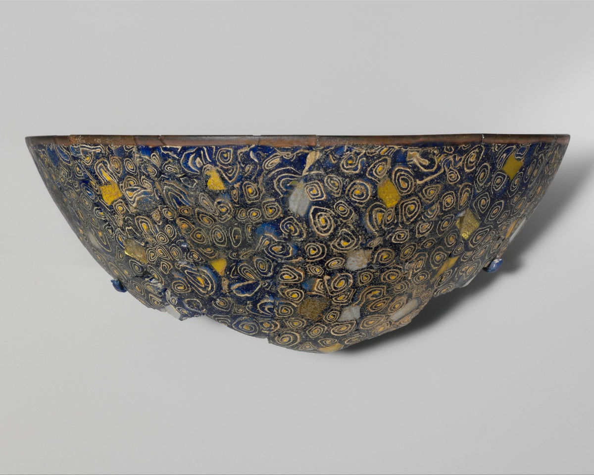 Ancient gold-glass mosaic bowl fragment with luminous metallic bands and dark glass sections.