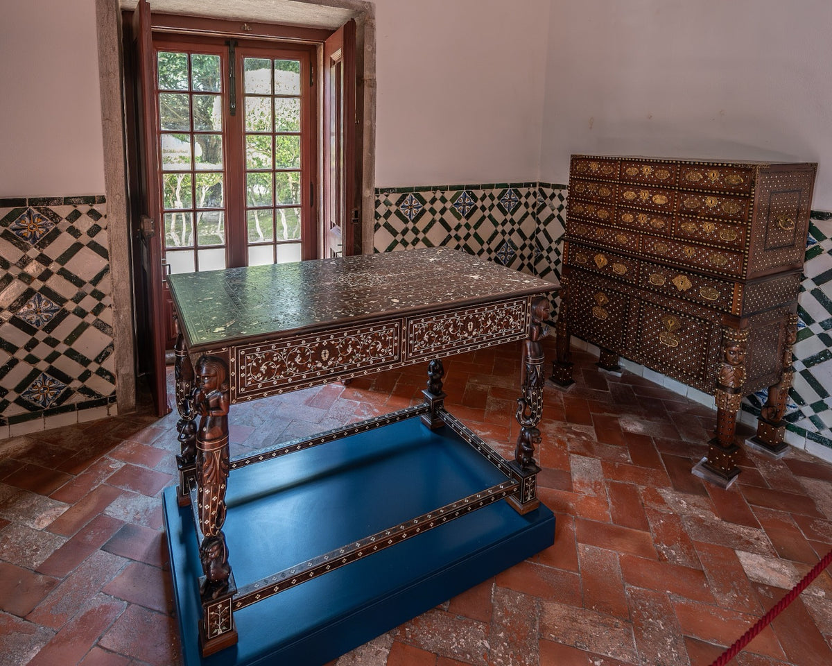 A room with geometric wall tile, terracotta herringbone floor, and richly inlaid furniture demonstrating pattern at several distinct scales.