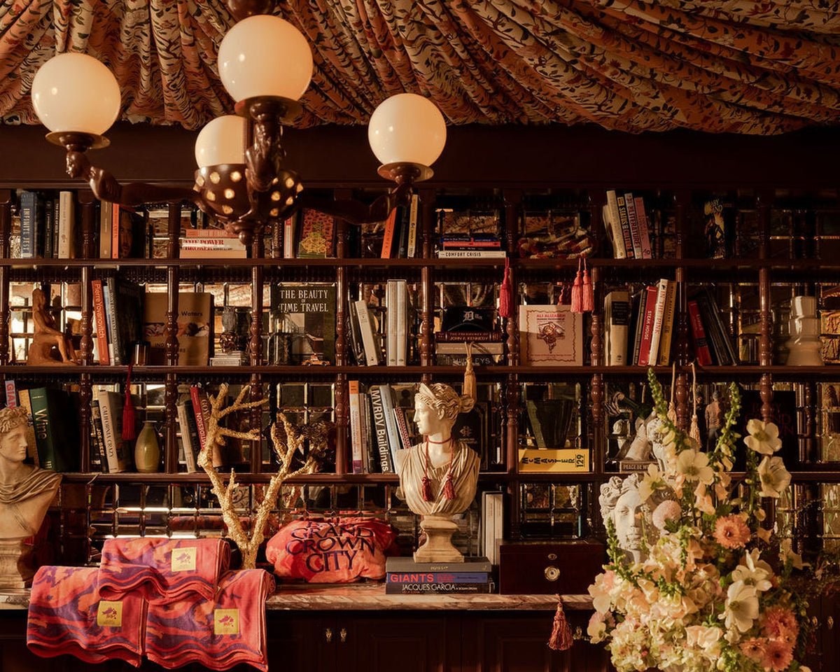 The Baby Grand lobby layered with books, marble, sculpture, and a fabric ceiling