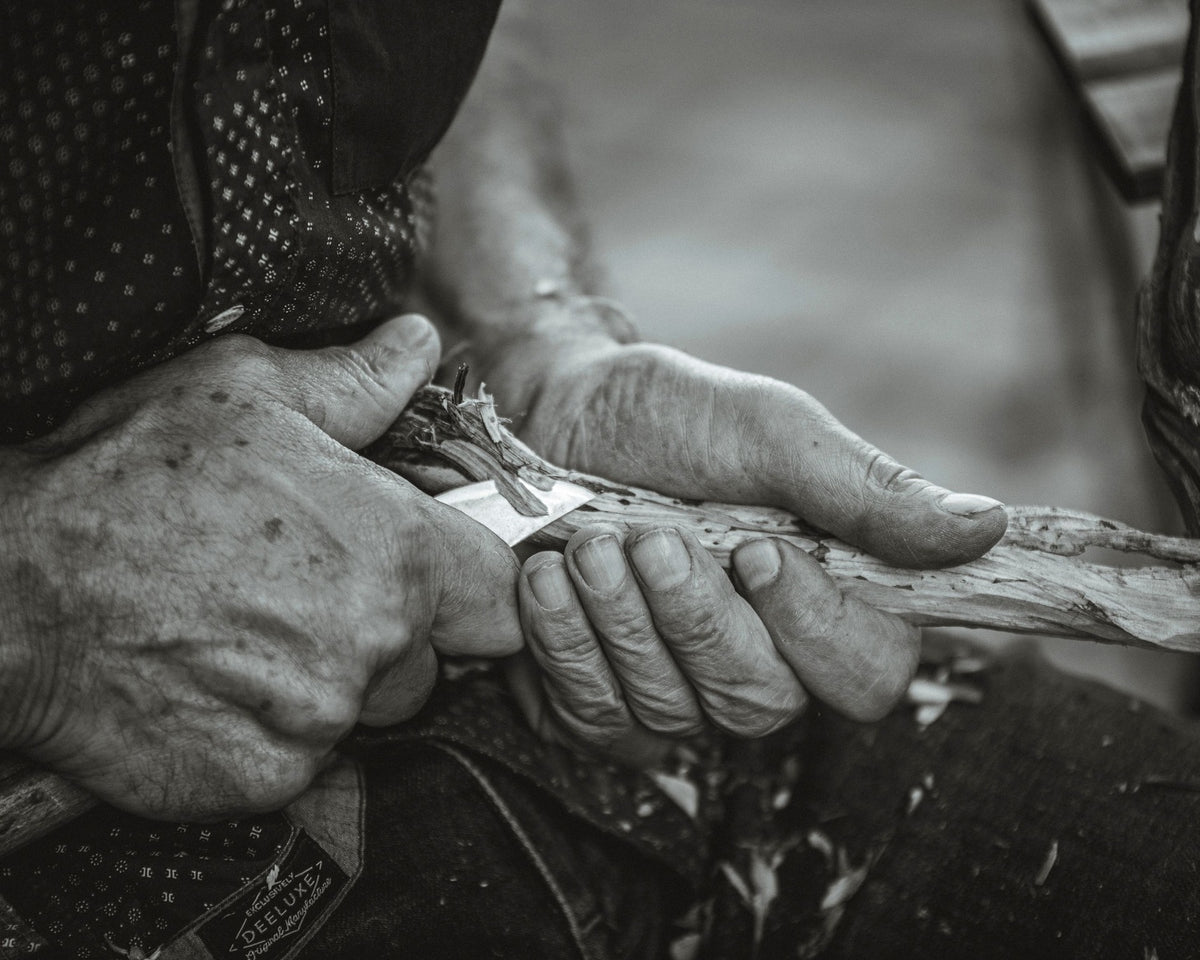 Artisan's hands carving wood with a traditional hand tool