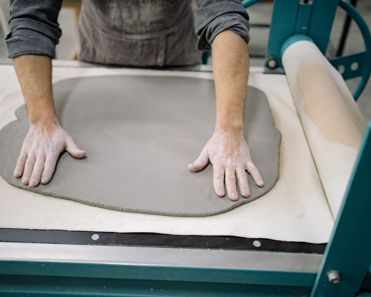 Ceramic maker pressing and adjusting a clay slab by hand