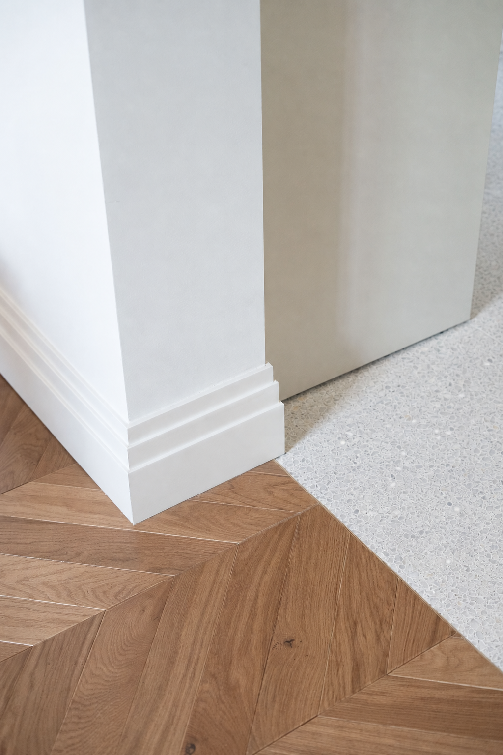Scarecrow terrazzo tile installed at a white wall and wood floor transition